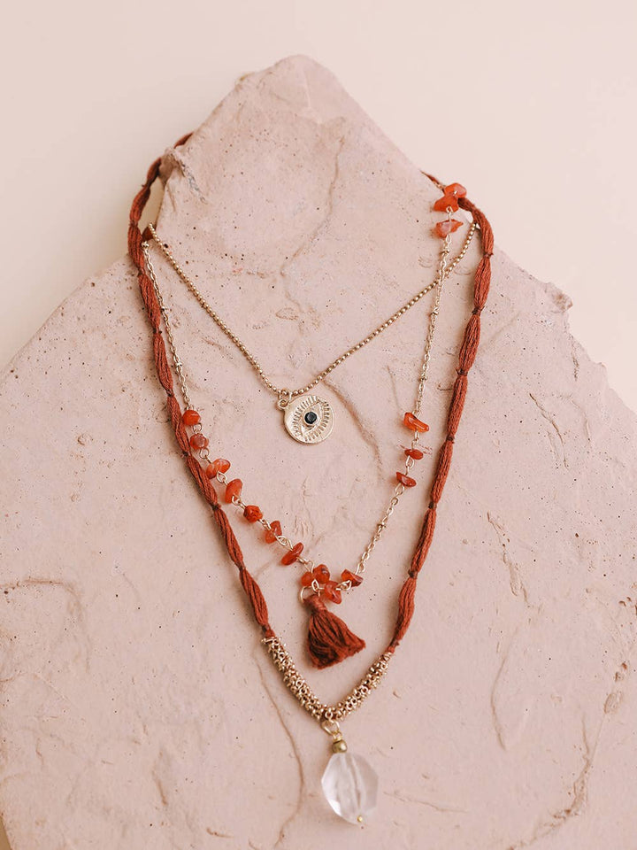 Boho Carnelian & Crystal Pendant Multi-Layered Necklace by Leto: Intricate multi-strand necklace with evil eye pendant, tassel, and crystal stone. A perfect statement piece for any occasion, adding mystique and flair to your ensemble. Shop now for a unique and trendy bohemian accessory.